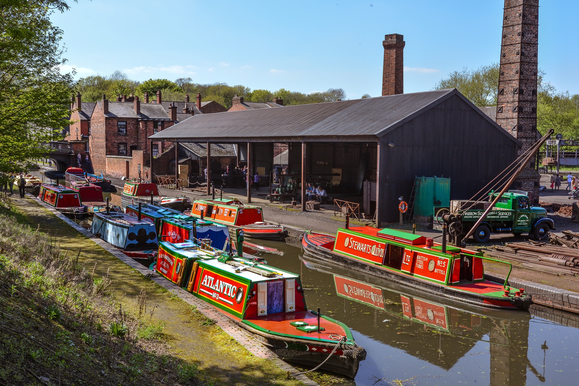 Tug boats sitting on a Black Country canal, with blue skies and industrial buildings in view.