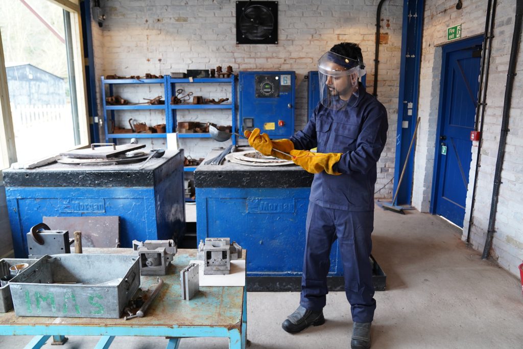 A costumed character dressed in overalls demonstrates in J.H. Lavender Aluminium Foundry, set in 1959.